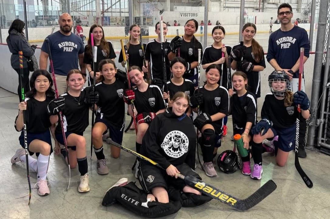 Girls ball hockey team with Aurora Prep coaches at the arena