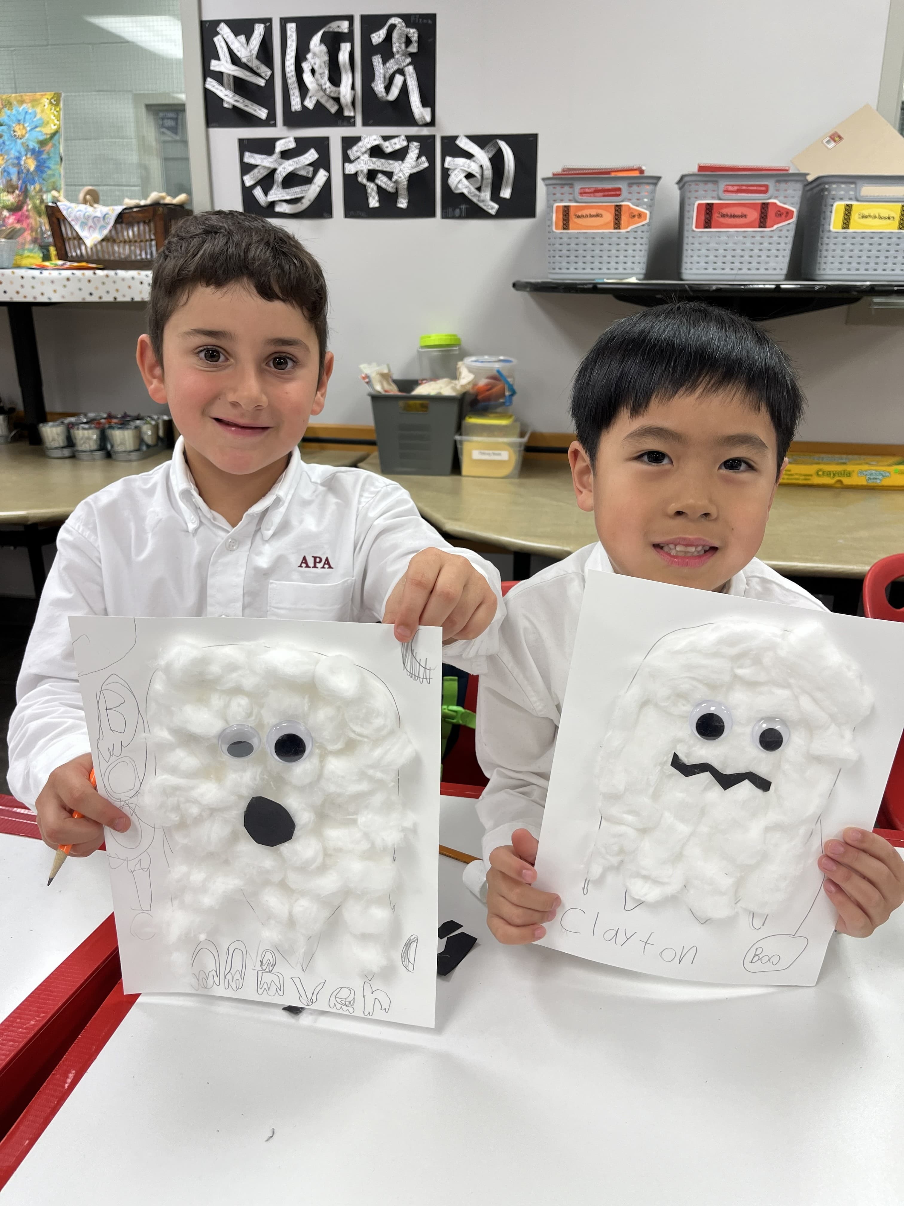 Two young boys proudly holding their cotton-ball ghost art projects